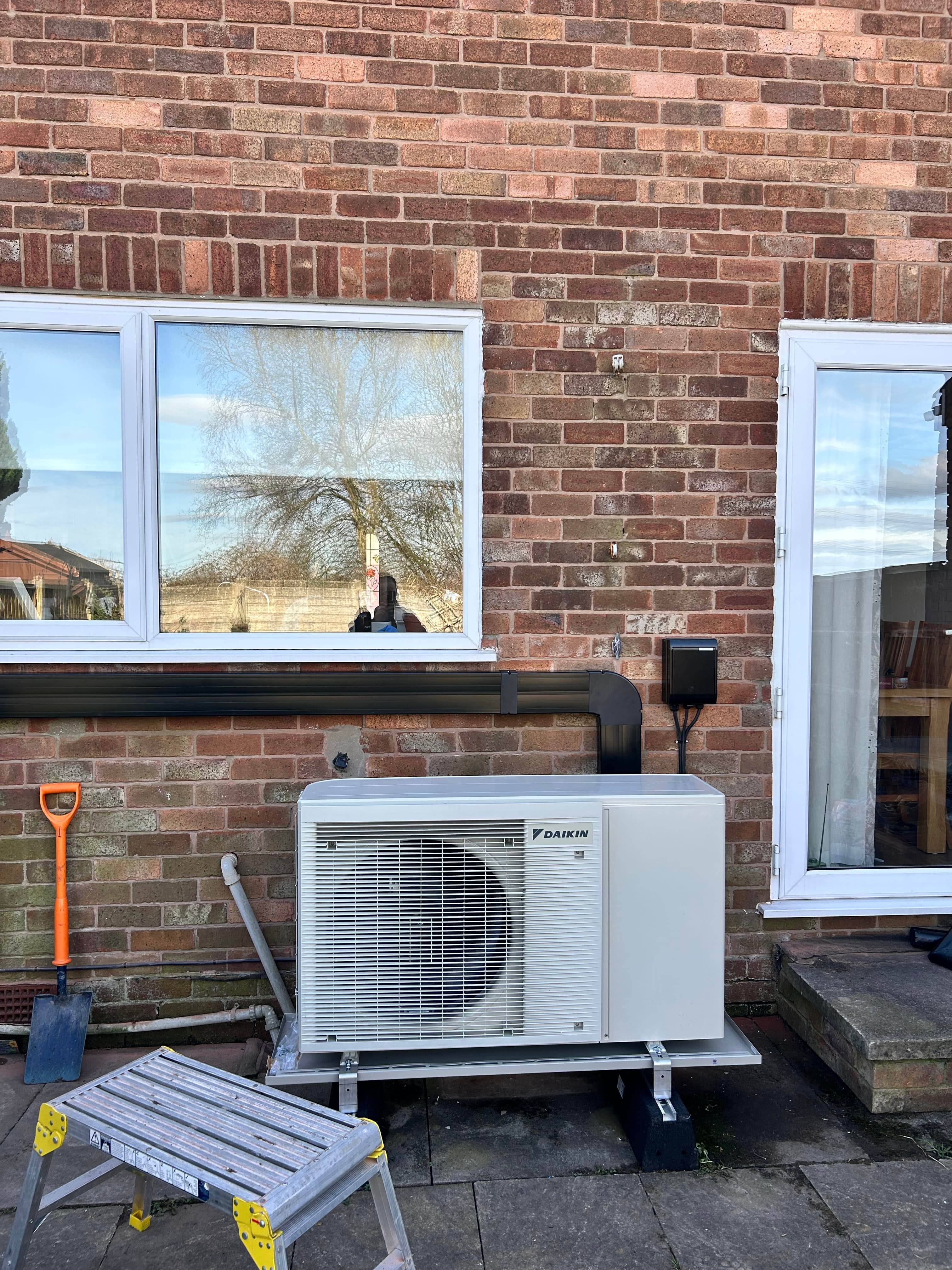 Daikin air source heat pump installed with neat external trunking on a brick house